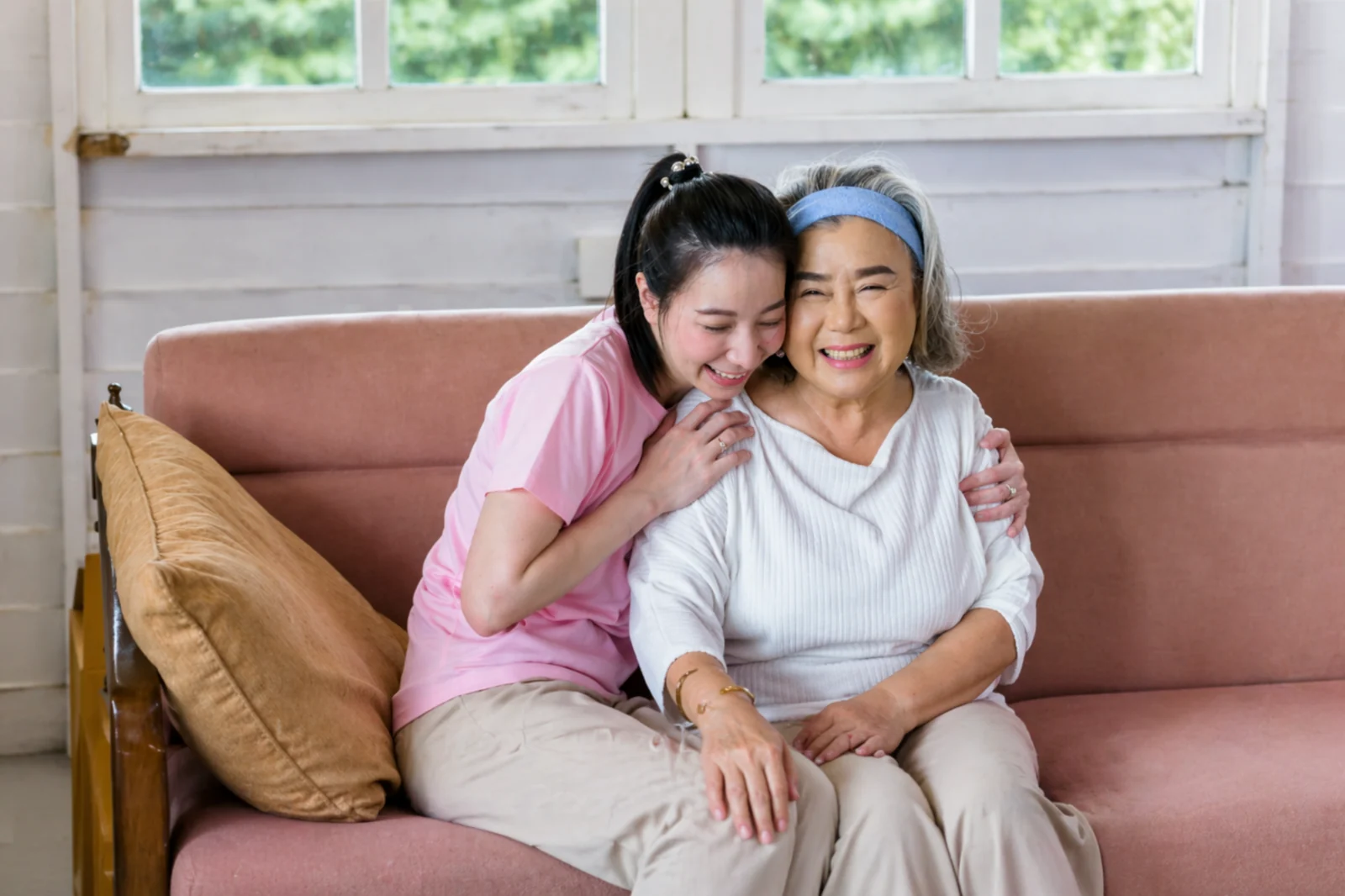 Opiekunka obejmująca starszą kobietę na kanapie w domowym otoczeniu