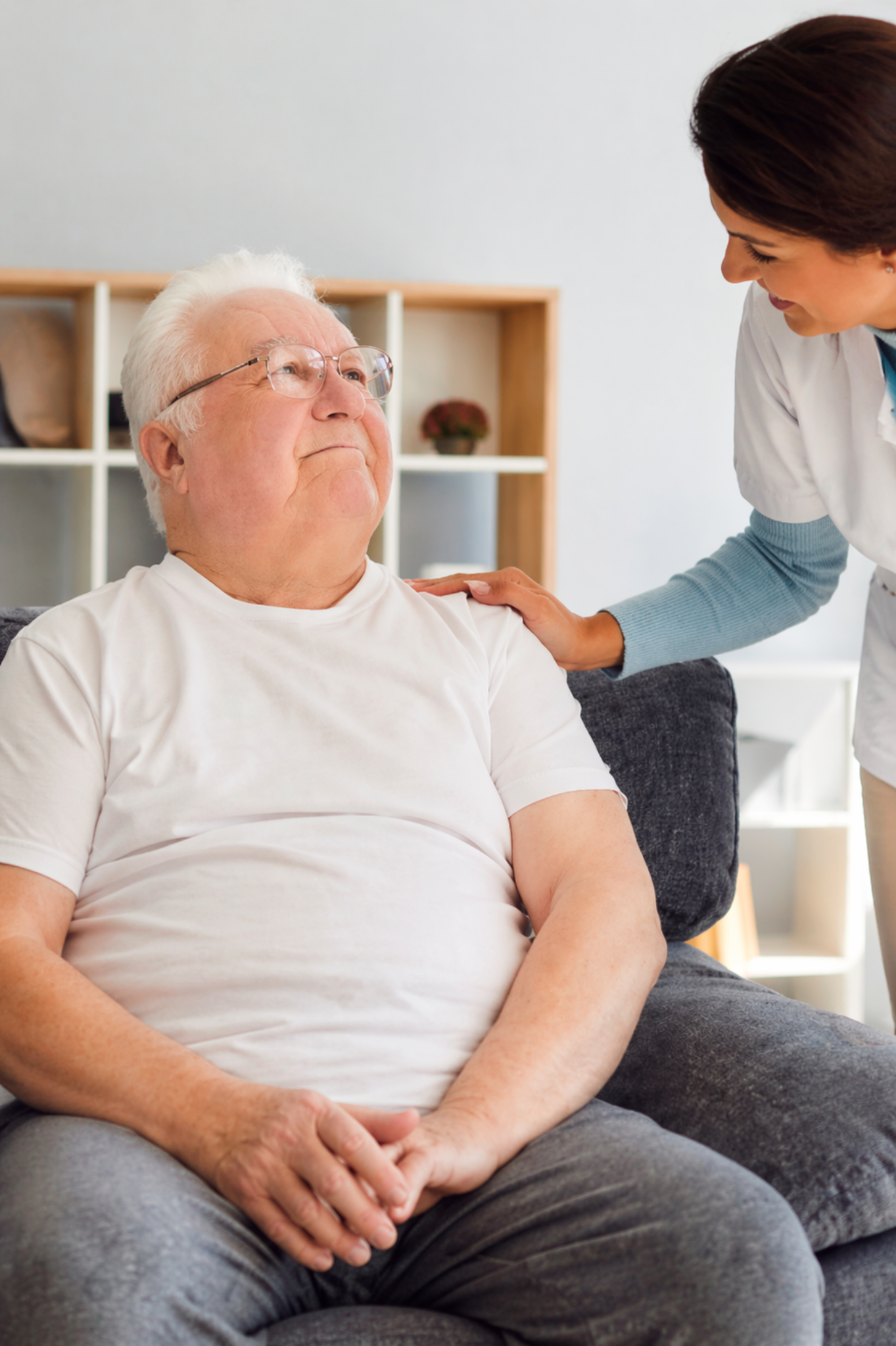 Opiekunka rozmawia ze starszym mężczyzną siedzącym w fotelu